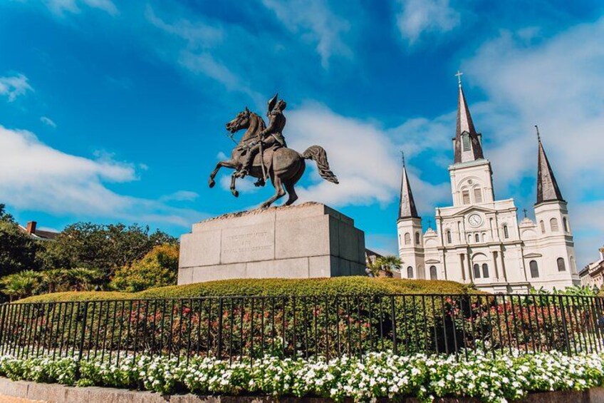 A statue of a person on horseback, a church with multiple spires, and a well-maintained garden with white flowers. 2