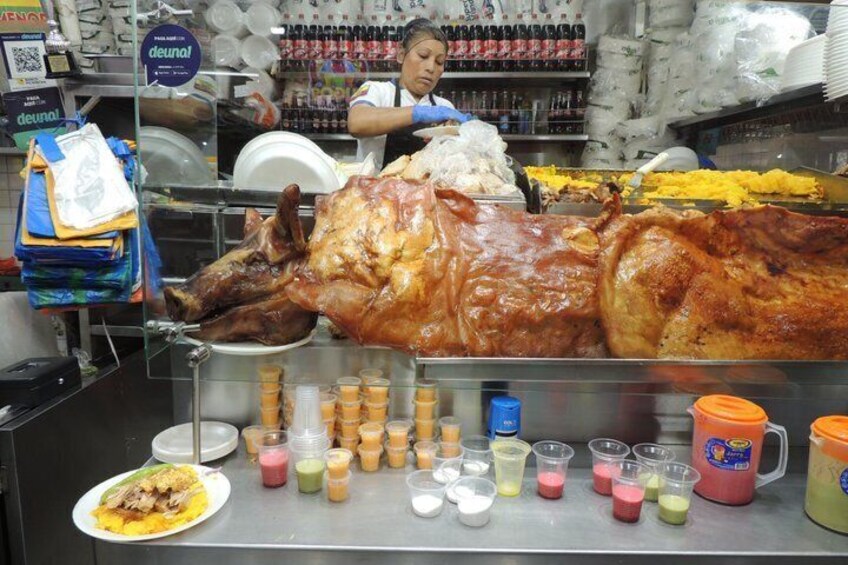 A large roasted pig, a variety of colorful drinks, and a person in a white shirt behind the counter. 4