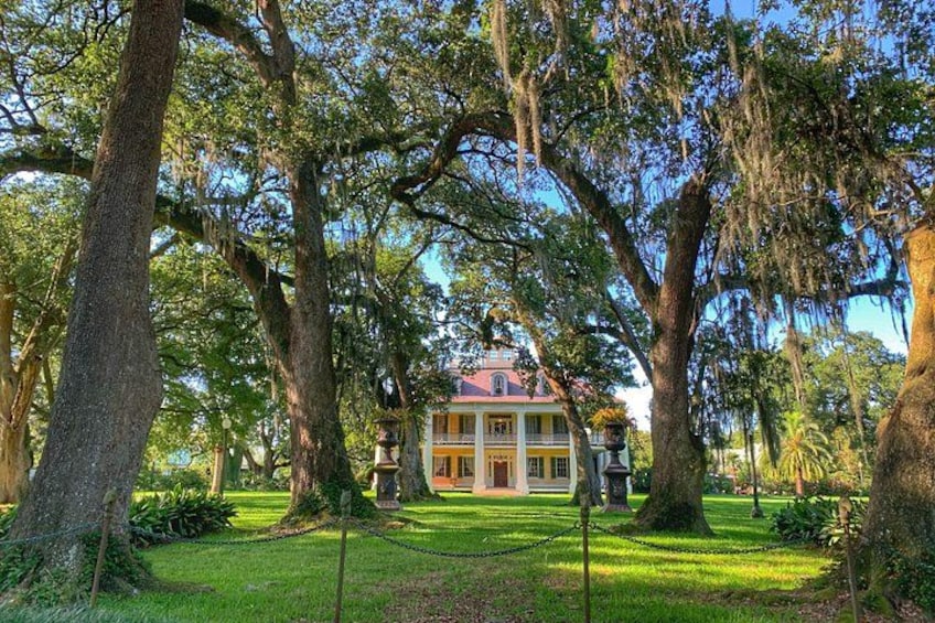 A historic house surrounded by large trees with a well-maintained lawn. 4