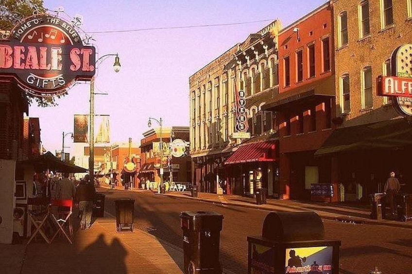 A street with vintage buildings, a neon sign for Beale St. Gifts, and a vintage car. 2