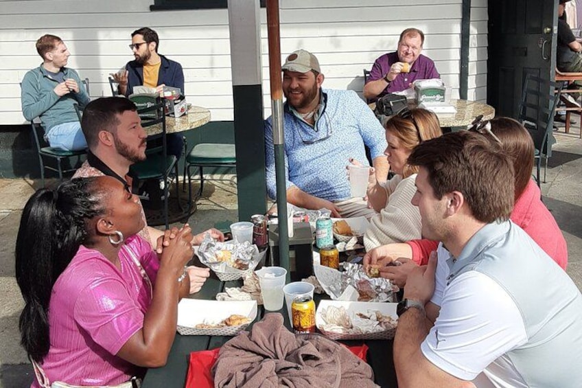 A group of people sitting around a table outdoors, eating and drinking. 5