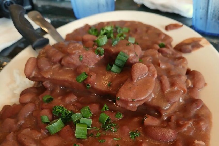 A plate of beans and sausage with green onions on top. 4