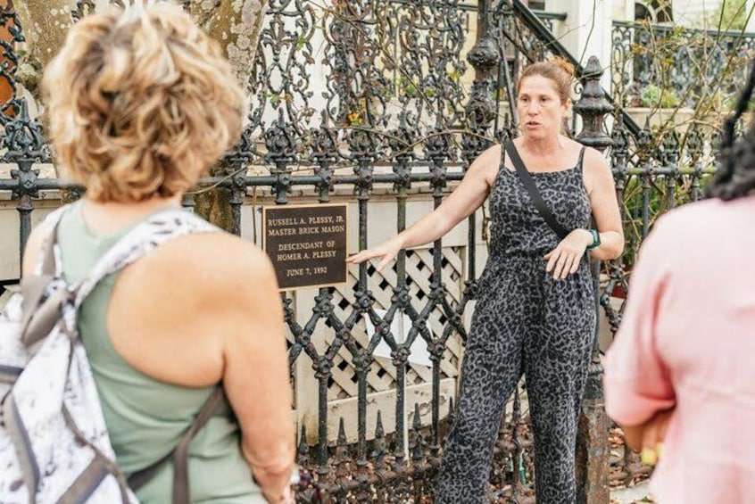A person standing in front of a wrought iron fence with a sign. 3