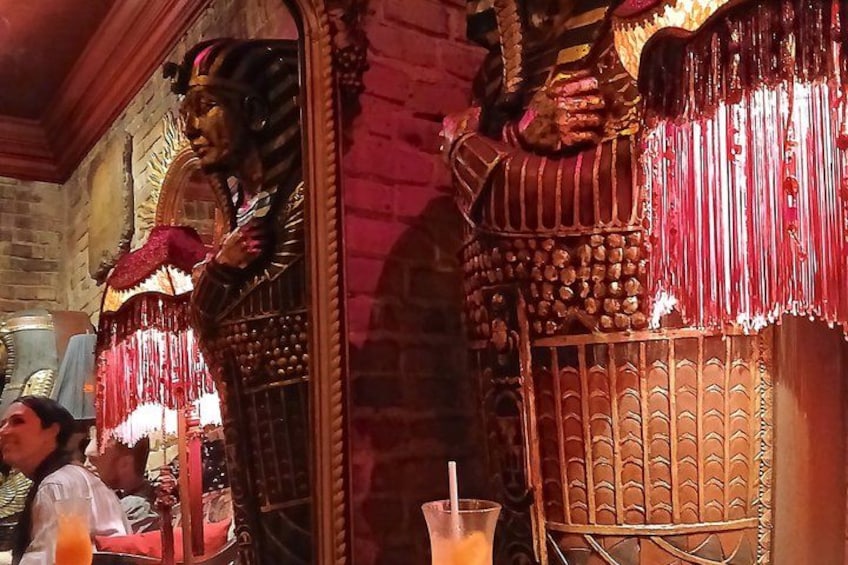 Detalles arquitectónicos ornamentales, una persona con vestimenta tradicional y una bebida sobre una mesa. 4