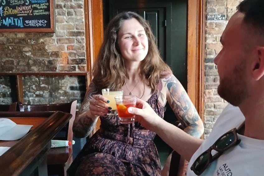 Una persona sosteniendo una bebida con pajita, sentada a una mesa en un local de paredes de ladrillo. 1