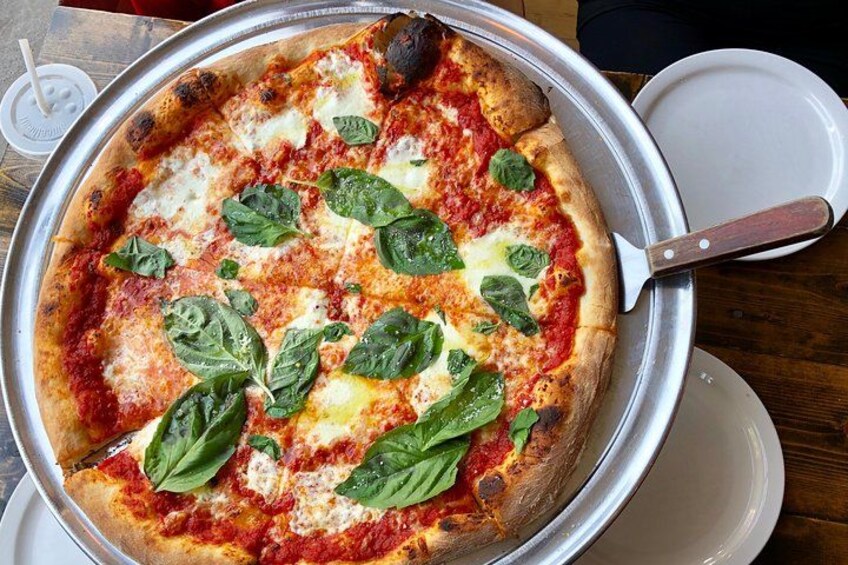 A pizza with tomato sauce, cheese, and basil leaves on a metal tray. 4