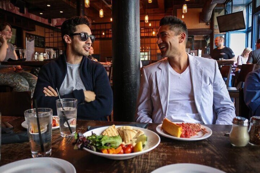 Two men dining at a restaurant with a variety of dishes on the table. 1