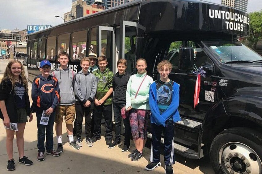 En gruppe mennesker står foran en sort bus med teksten 'UNTOUCHEABLE TOURS'. 2