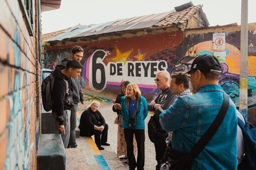 A mural with the text "6 de Reyes" and people standing in front of it. 1
