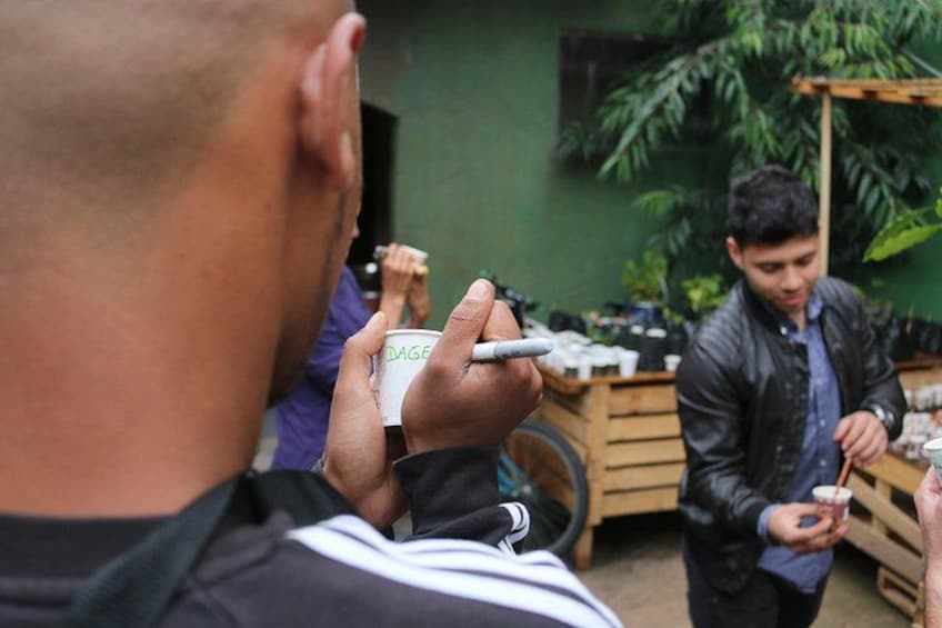 A person holding a cup with a straw, another person in the background holding a drink, and a bicycle. 5