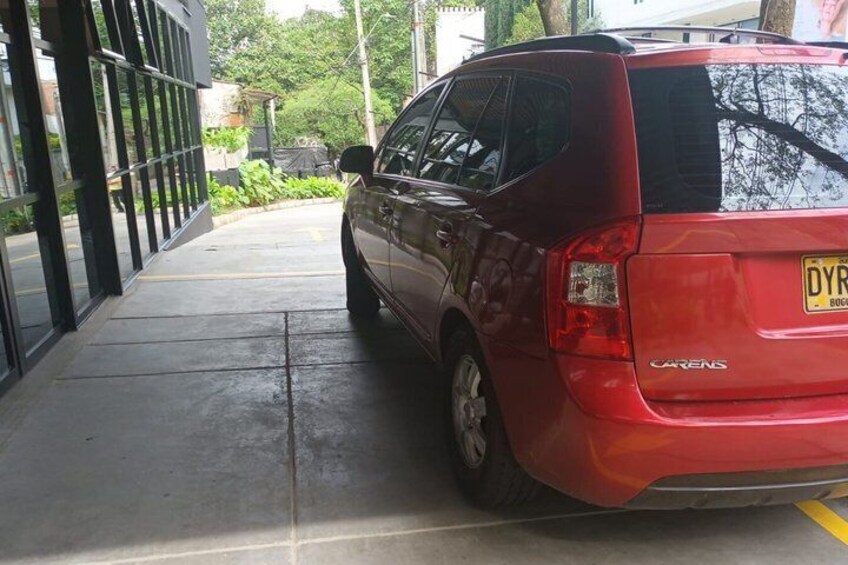 Un auto rojo estacionado en un área de estacionamiento techada, con una placa de matrícula visible. 4