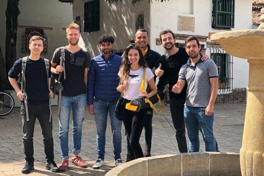 A group of people standing in a courtyard with a fountain in the foreground. 1
