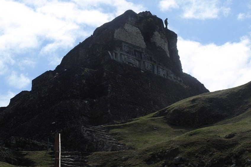 Une montagne surmontée d’une grande formation rocheuse et, au premier plan, un mât portant un drapeau. 2