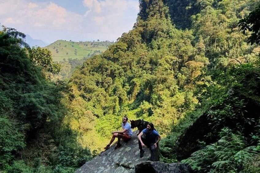 A person sitting on a rock in a lush green valley. 2