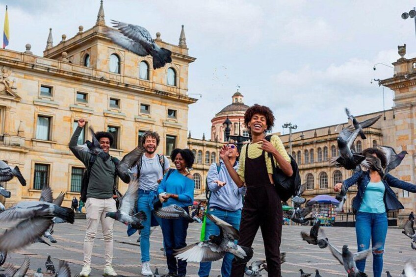A group of people feeding pigeons in a plaza with historic architecture in the background. 3