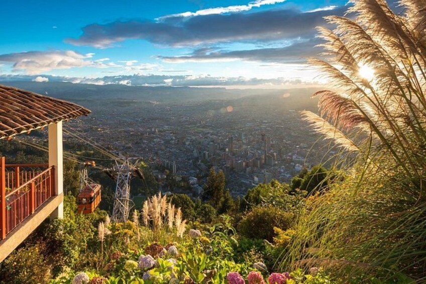 A panoramic view of a city from a high vantage point with a cable car, vegetation, and a clear sky. 2