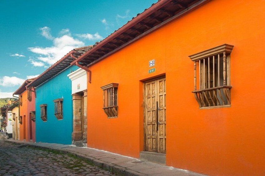 A street with colorful buildings, a cobblestone path, and a clear blue sky. 2
