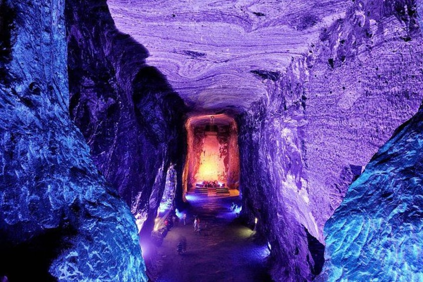 A tunnel with a train at the end, surrounded by rocky walls. 1