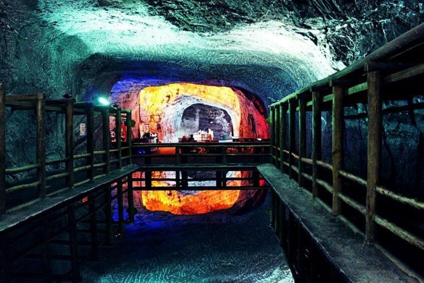 A cave with a wooden walkway and a glowing rock formation. 4