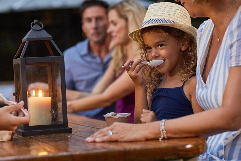 Een gezin zit aan een houten tafel met een brandende kaars en lantaarn. 4