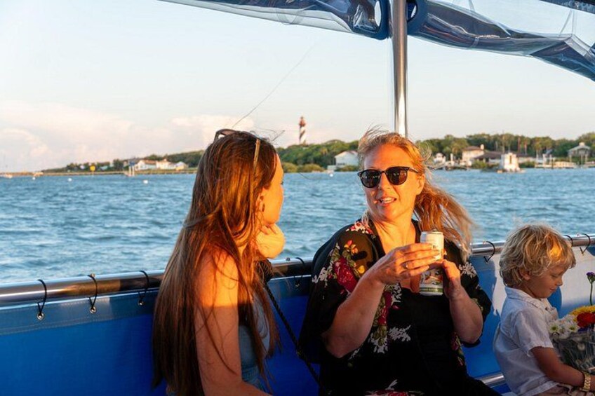 Un bote con personas a bordo, una masa de agua y una costa distante con edificios. 4
