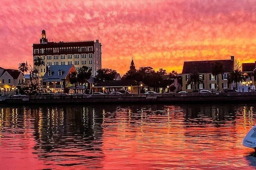 Un paisaje urbano frente al agua al atardecer, con edificios reflejándose en el agua. 1