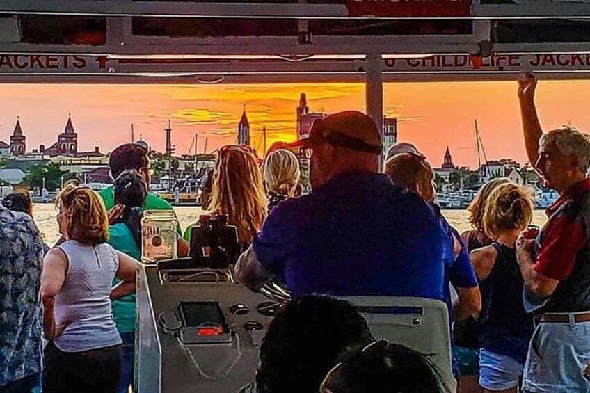 Un grupo de personas en un barco, un atardecer y un paisaje urbano con edificios. 3