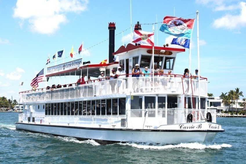 A large white riverboat with multiple decks and flags, including the American flag, sailing on water. 1