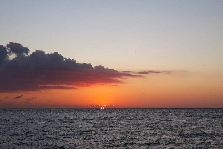 A sunset over the ocean with clouds and a boat. 4