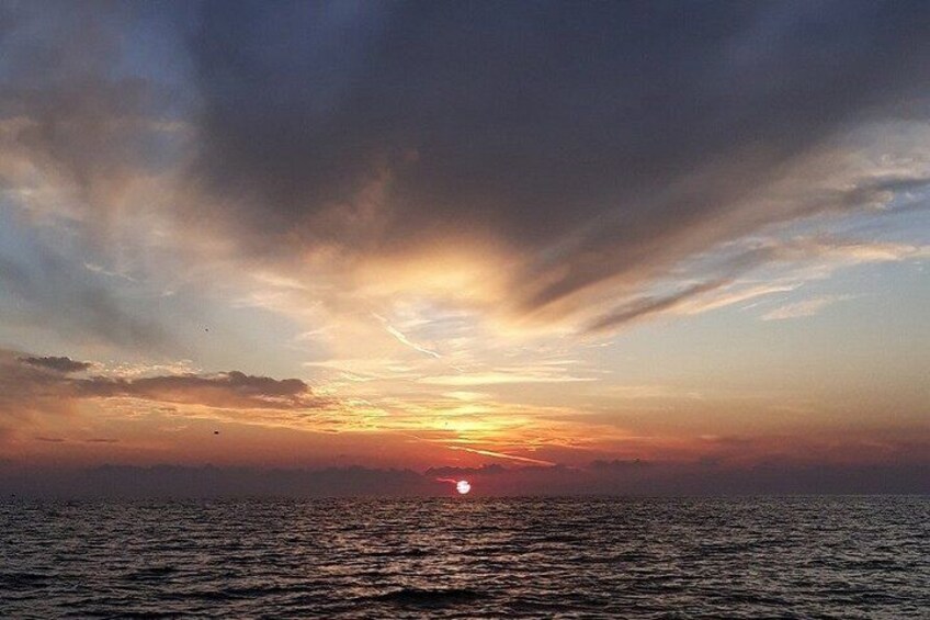 A sunset over a body of water with clouds in the sky. 3
