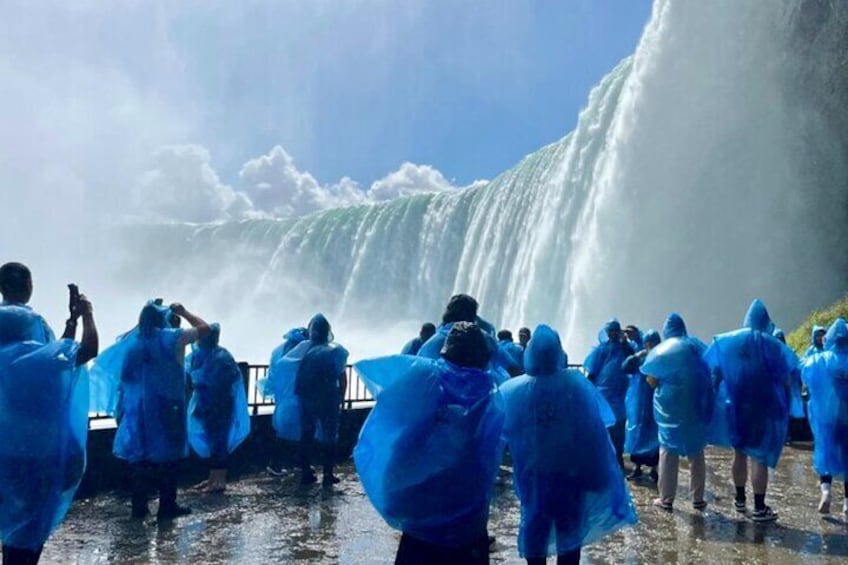 A group of people in blue raincoats standing in front of a waterfall. 1
