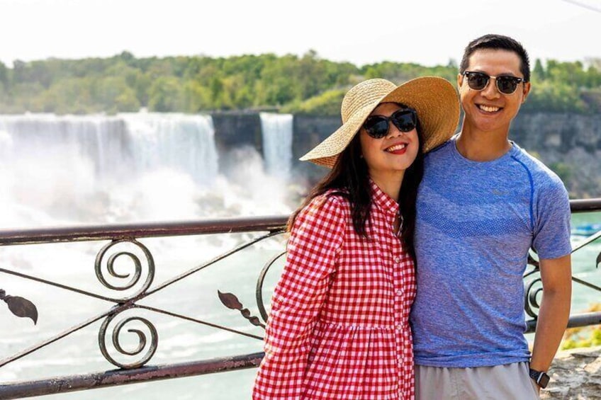 A couple standing by a railing with a waterfall in the background. 5