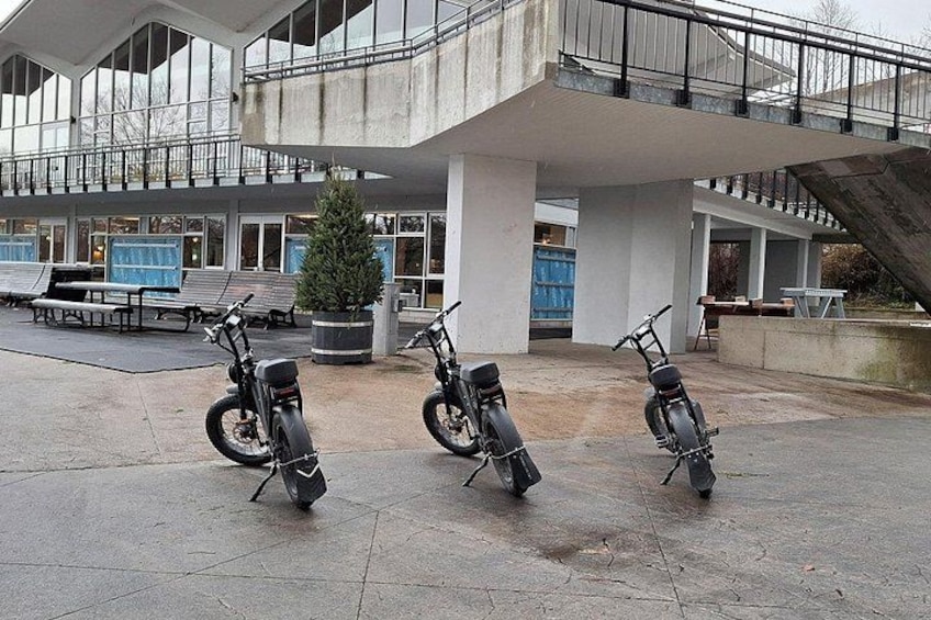 Drei Fahrräder stehen vor einem modernen Gebäude mit einer großen Treppe und einem Weihnachtsbaum. 2