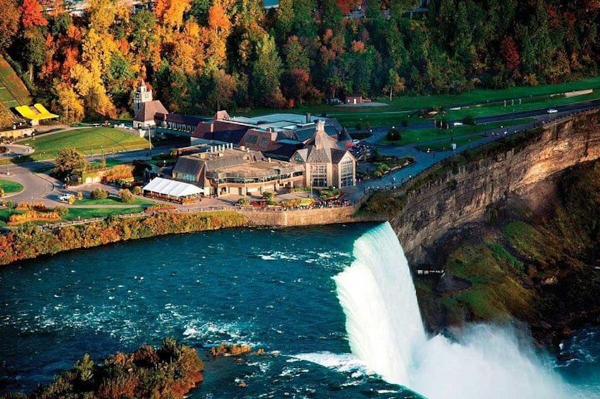 A waterfall, a river, and a building complex surrounded by autumn foliage. 1