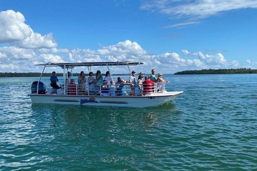 Een boot met mensen op kalm water, omgeven door een heldere lucht en veraf gelegen land. 4