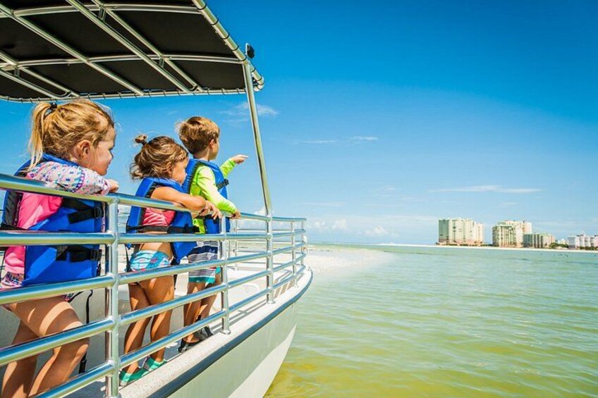 A boat with passengers wearing life jackets, a clear sky, and a distant cityscape. 5