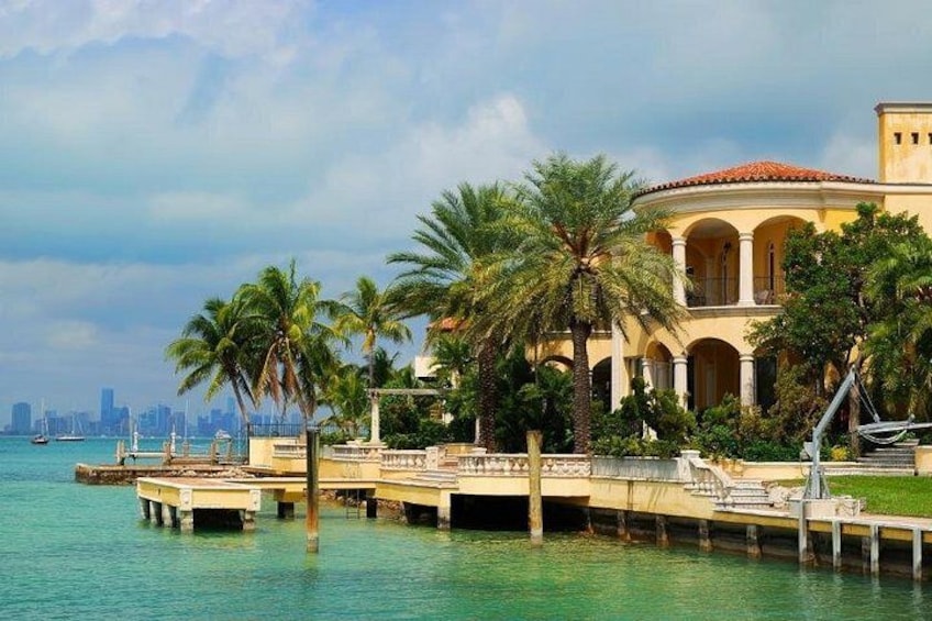 A waterfront property with palm trees, a pier, and a city skyline in the background. 5