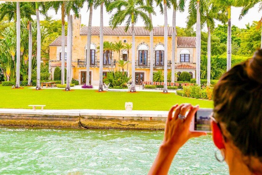 Une personne prend une photo d’un grand bâtiment historique, doté d’une pelouse bien entretenue et de palmiers. 3