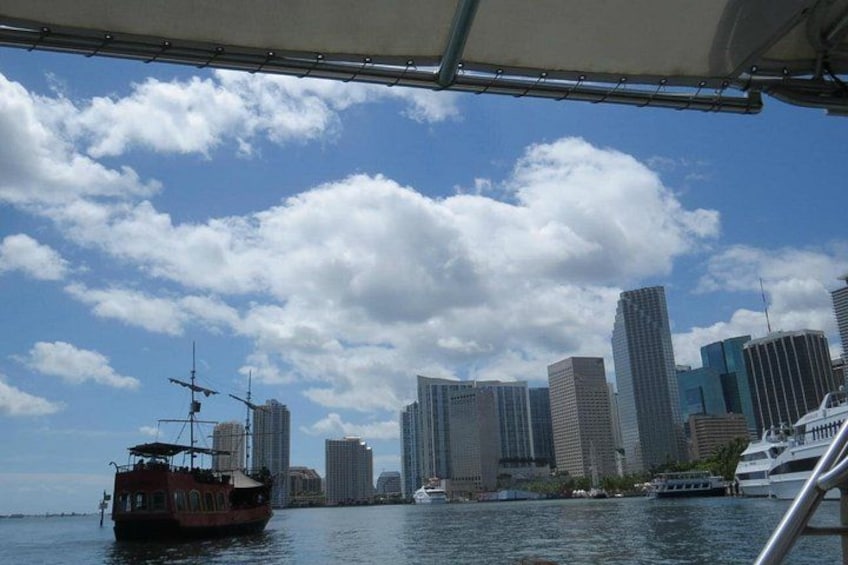 A city skyline with tall buildings and a boat in the foreground. 4