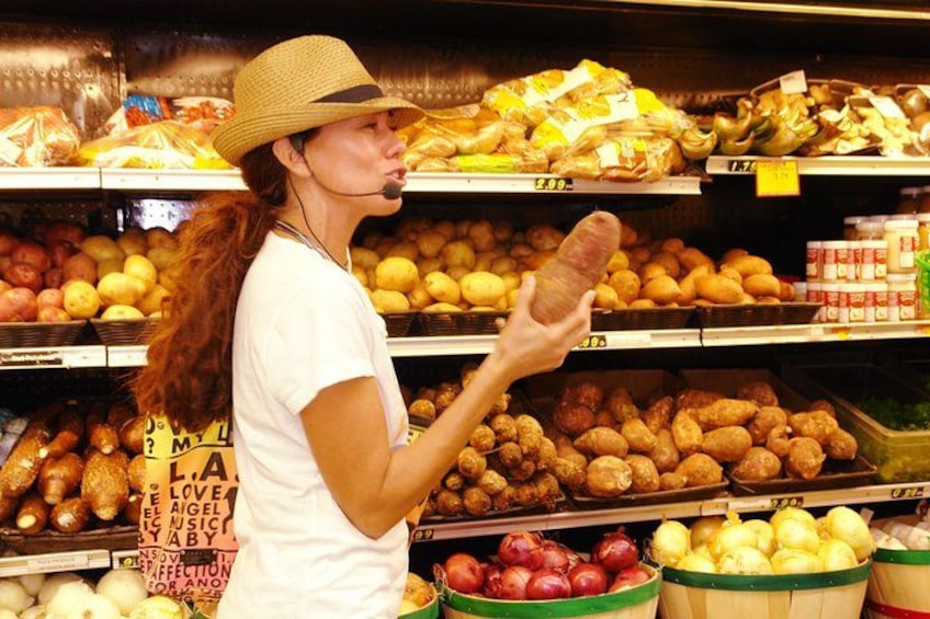 A person in a grocery store aisle with various produce items like potatoes, onions, and bananas. 1