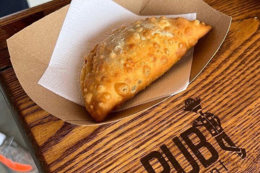 A fried pastry in a paper container on a wooden table. 5