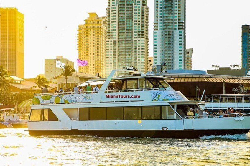 A boat with MiamiTours.com branding, passengers, and a city skyline in the background. 4