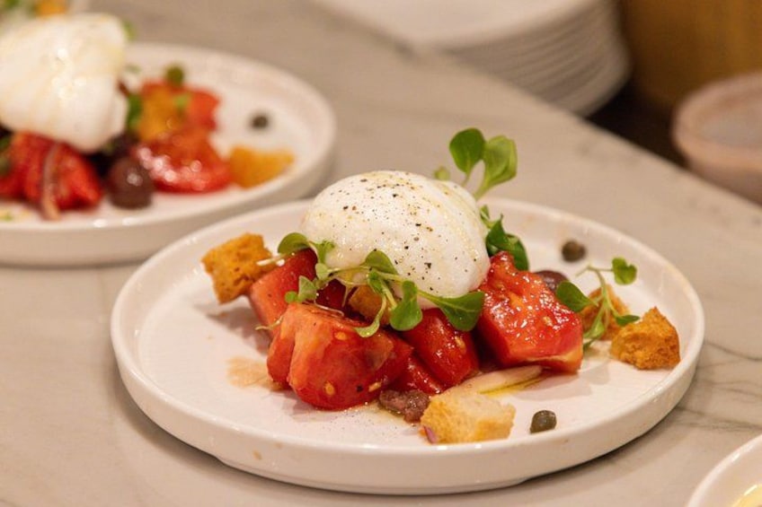 Een bord eten met gepocheerd ei, tomaten, groen en croutons. 3