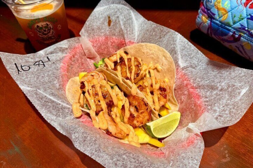 Two tacos with a side of fries and a lime wedge on a paper-lined plate. 1