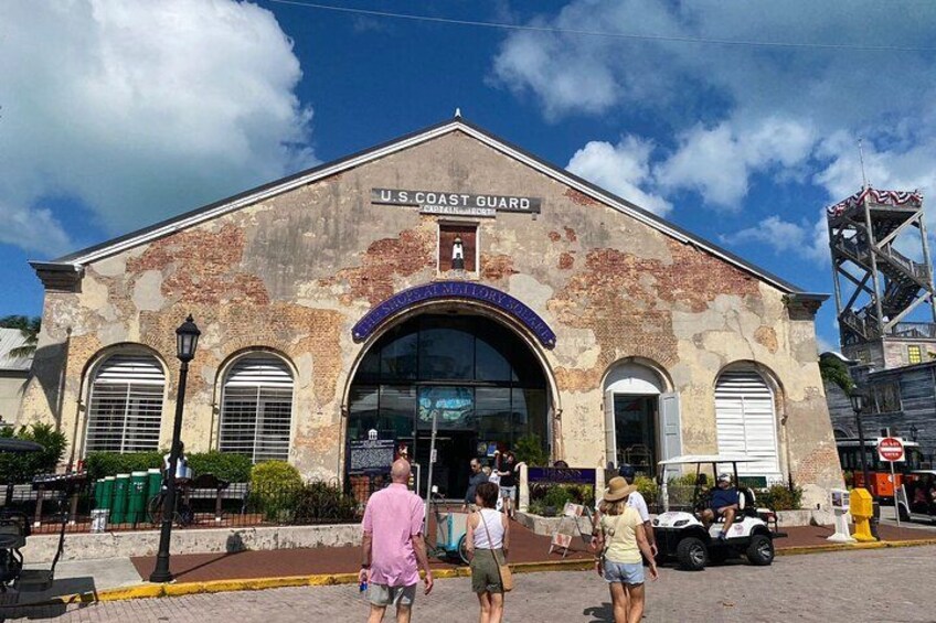 A U.S. Coast Guard building with a weathered facade, arched windows, and a prominent entrance. 5