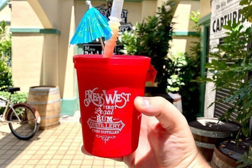 A red cup with a straw and a blue umbrella, labeled 'New West First Legal Rum Distillery.' 2