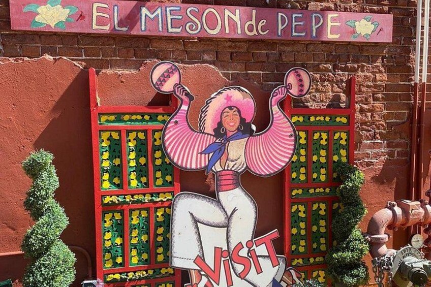 A colorful mural with a woman in traditional attire, a sign reading 'EL MESON de PEPE', and a 'VISIT' sign. 3