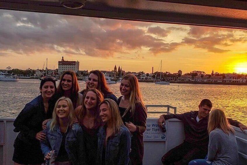 Un gruppo di persone su una barca con un tramonto su una marina. 1