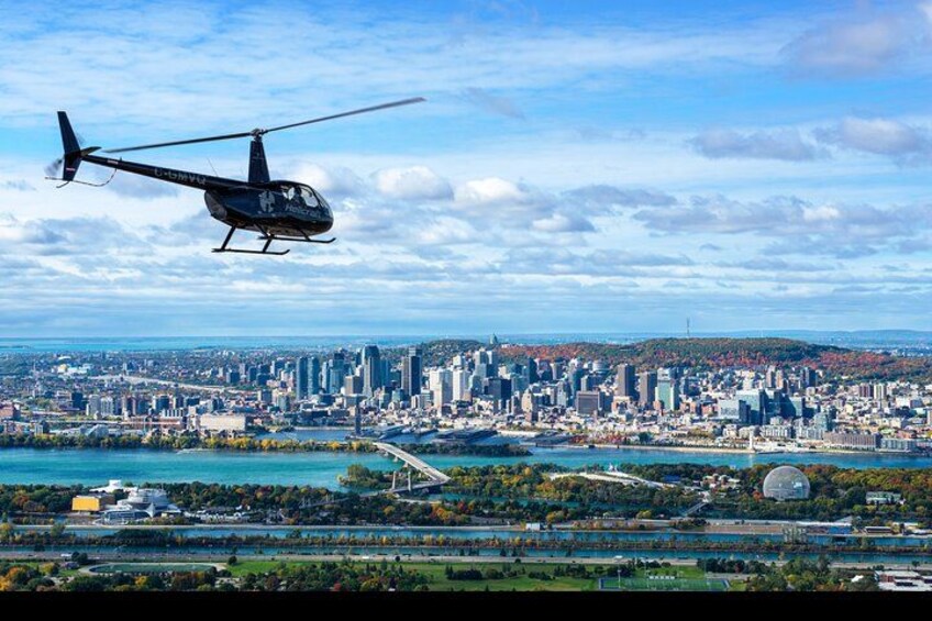 Un helicóptero vuela sobre una ciudad con un río y un puente. 1