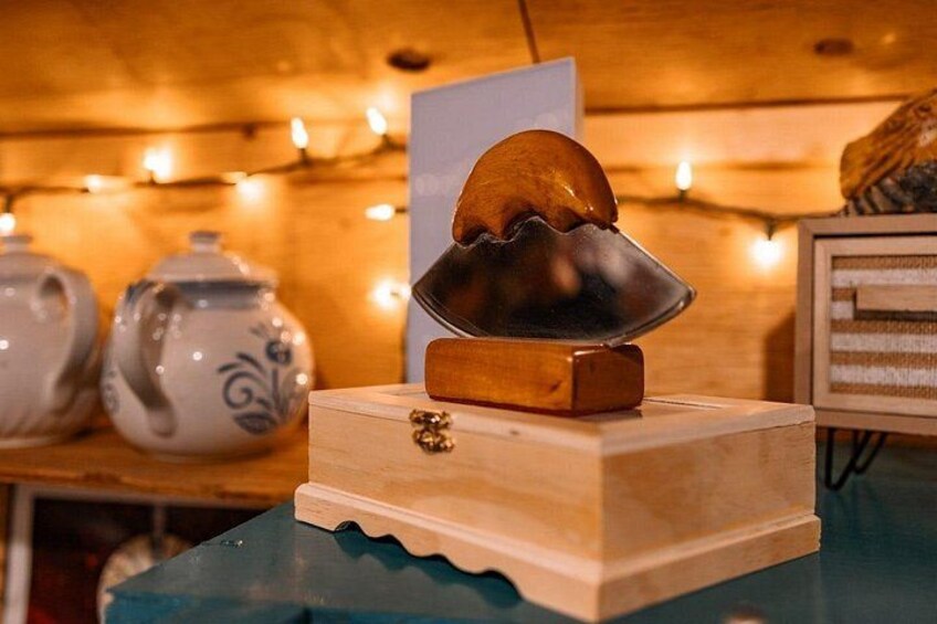 Une boîte en bois sur laquelle repose un objet en métal, un élément décoratif et, en arrière-plan, un tableau encadré. 5